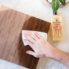 HOWARD pouring oil onto a wooden cutting board for restoration