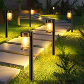 Mancra front view of ten metal and glass solar pathway lights showing warm white glow and decorative design