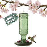 Perky-Pet front view of antique green glass bottle feeder showing decorative design and curb appeal