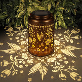 Tepaken front view hummingbird lantern showing warm glow and vintage finish enhancing ambiance