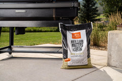 Traeger grill in use with visible smoke, showing clean flavorful burn