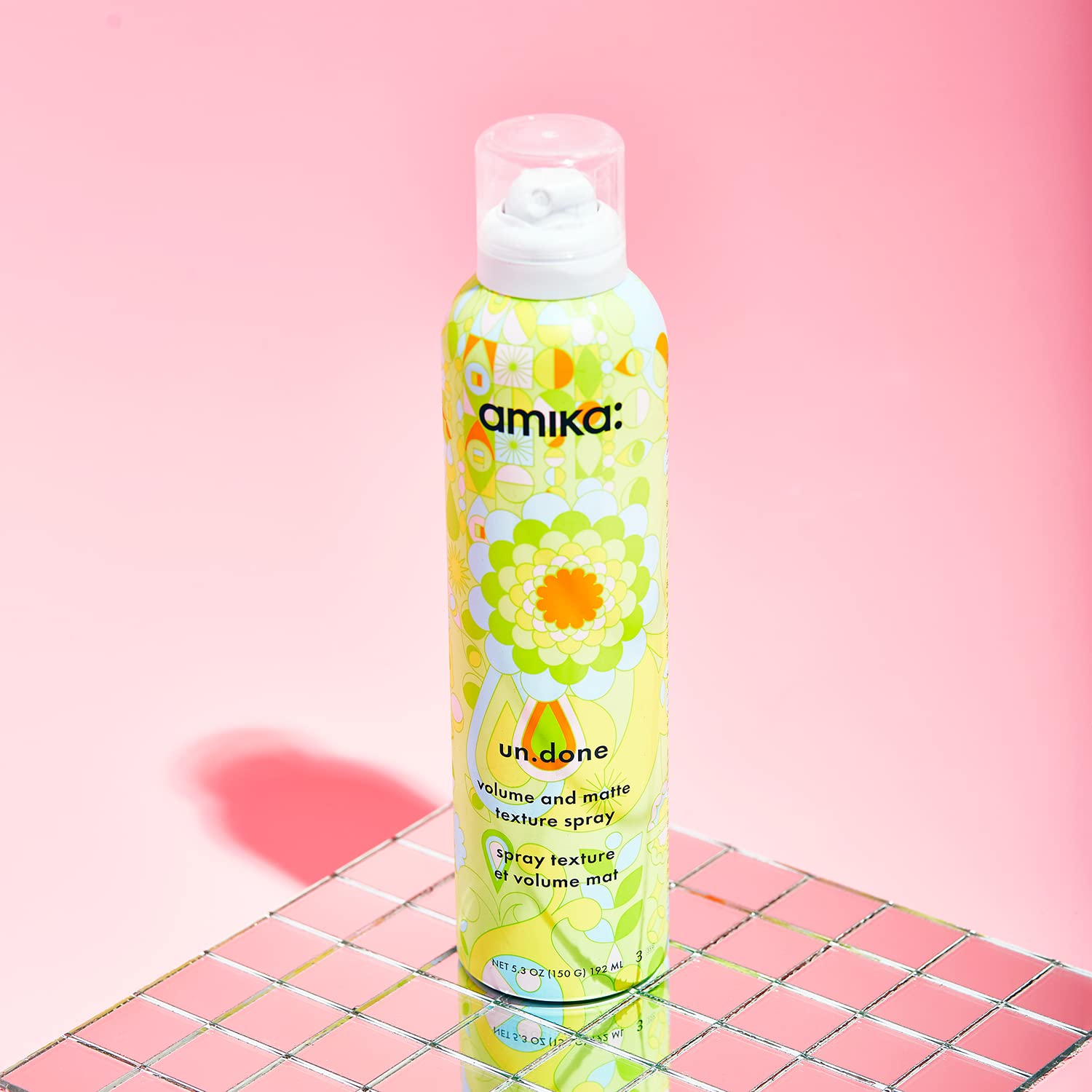 Amika un.done bottle next to hand displaying true size and portability