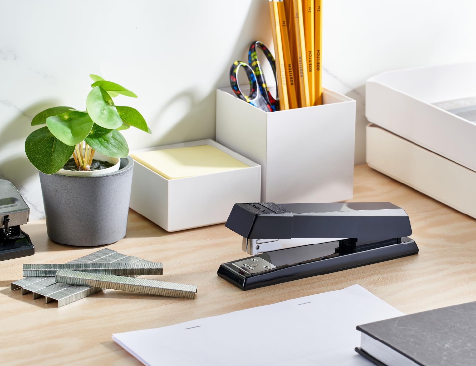 Bostitch stapler beside notebook showing scale for desktop convenience