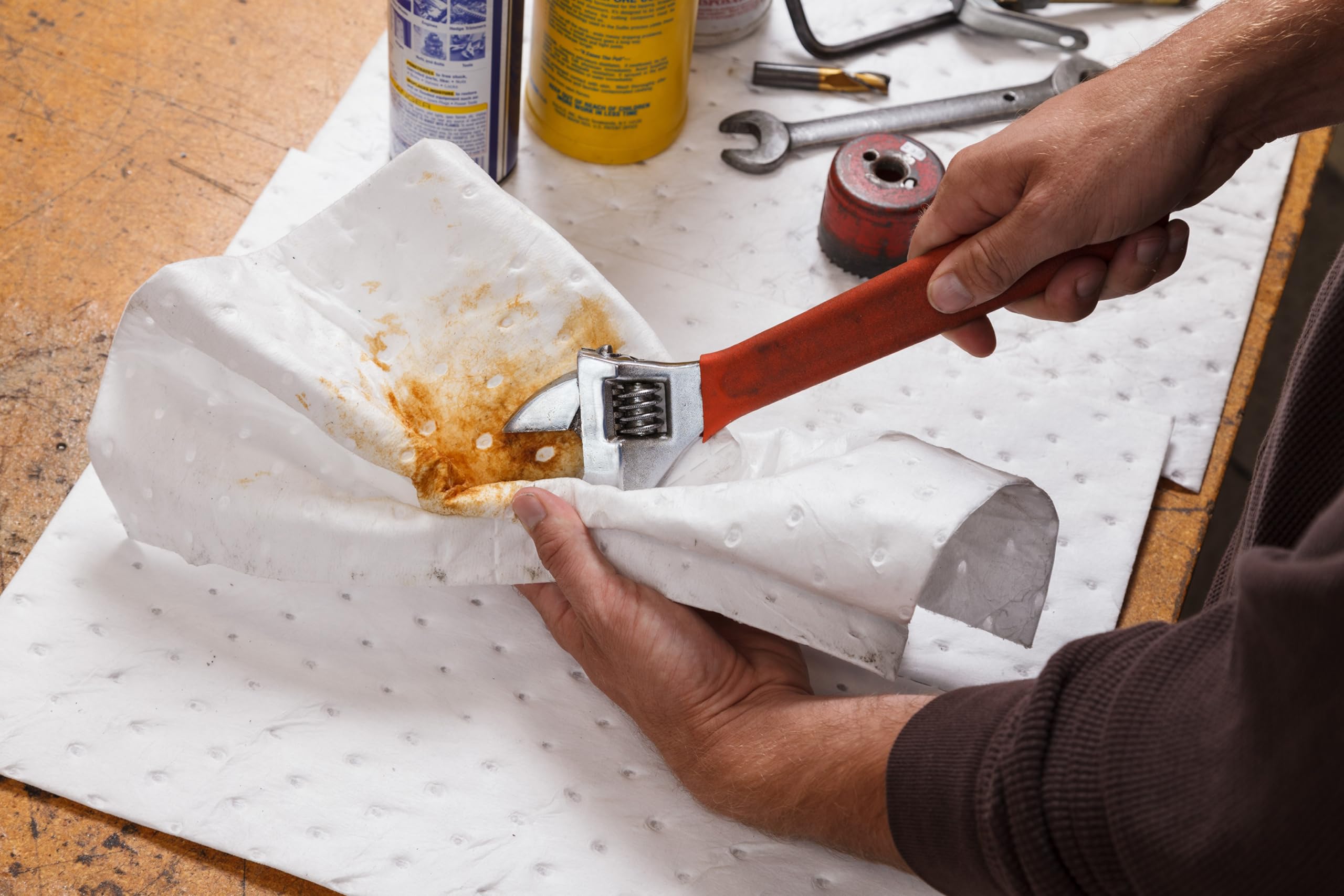 Brady pad absorbing oil on concrete floor to quickly clean leaks and reduce slip hazards