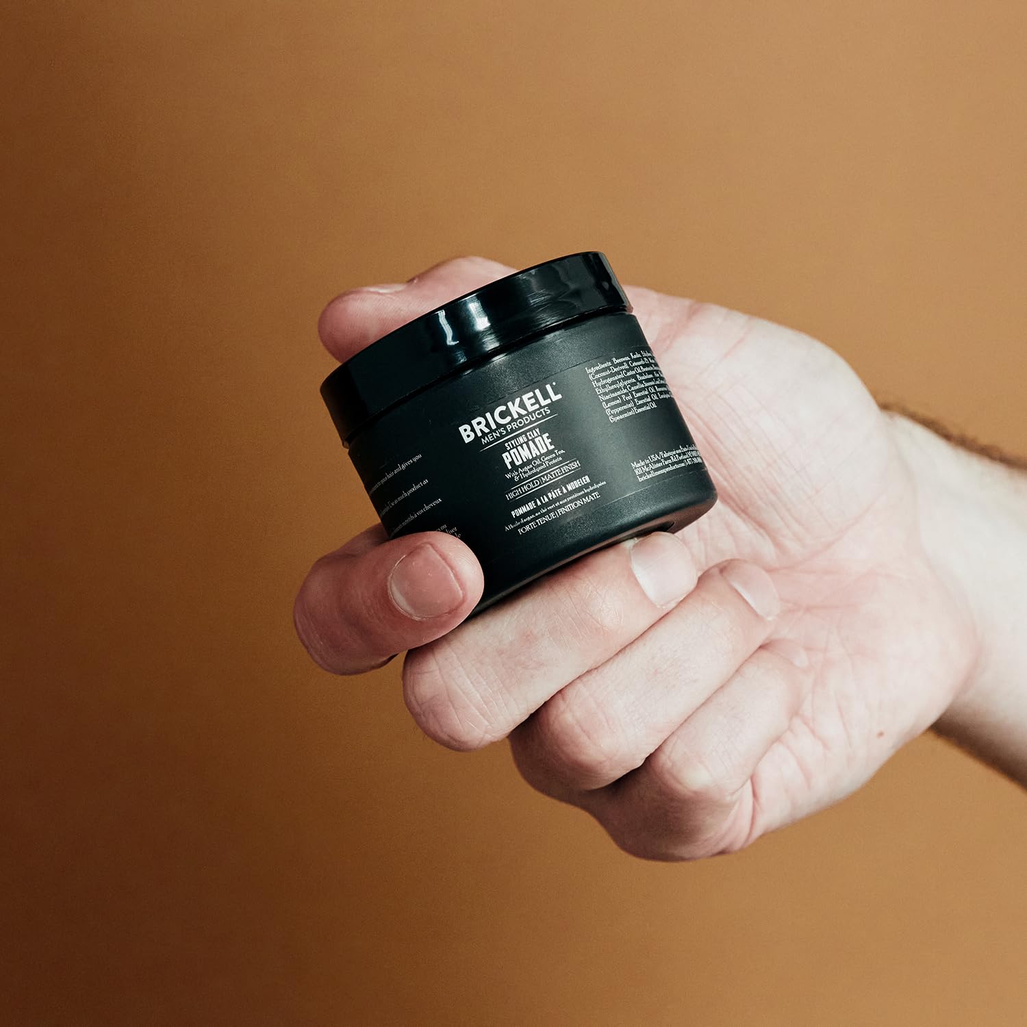 Hand applying Brickell pomade to hair demonstrating easy styling