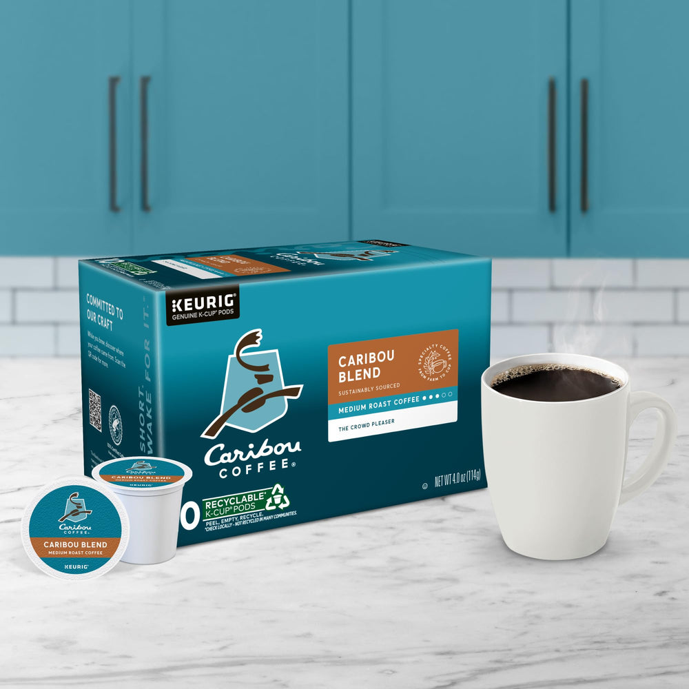 Hand holding a Caribou K-Cup next to a smartphone to show single-serve scale