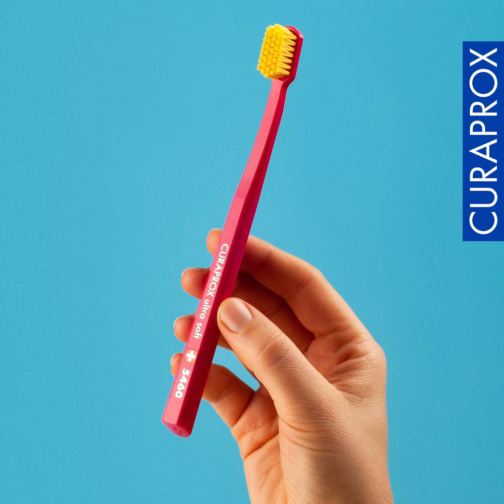 Curaprox toothbrush beside a hand demonstrating size and easy control for daily use