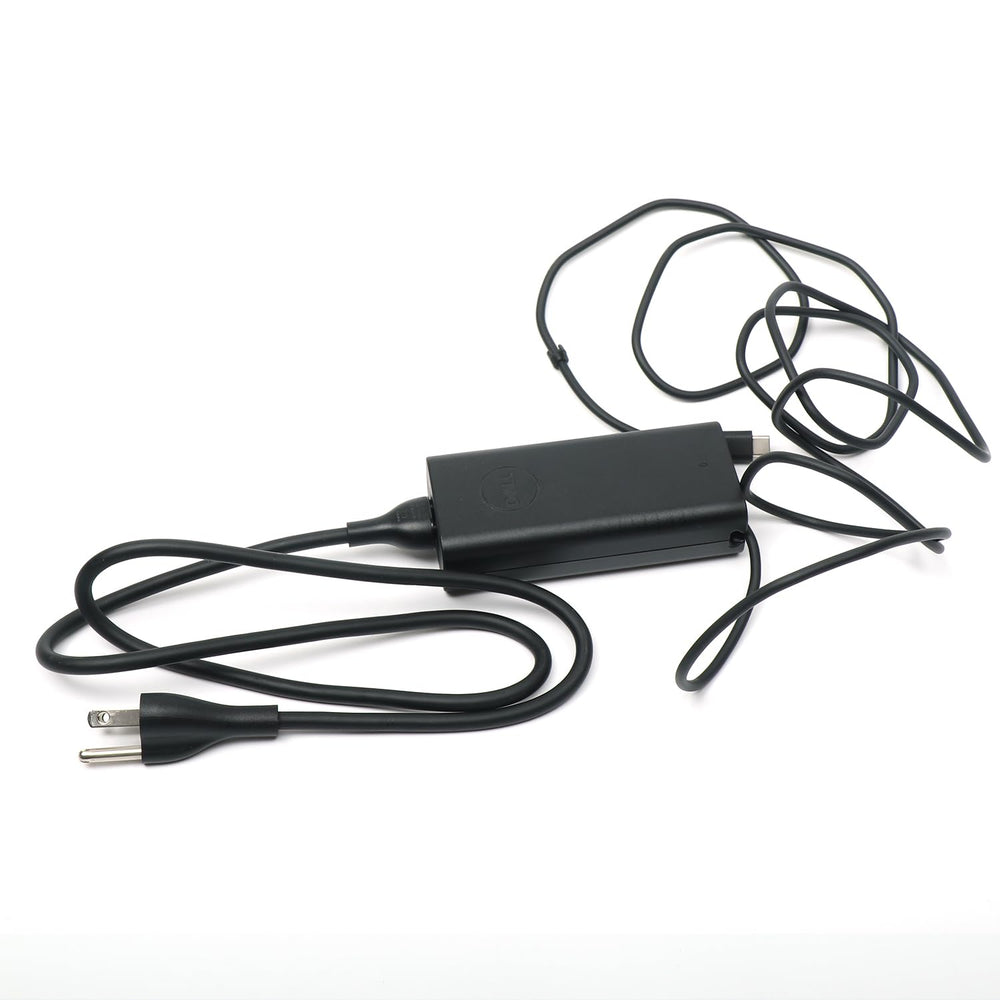Dell adapter beside a laptop to show compact size and travel convenience