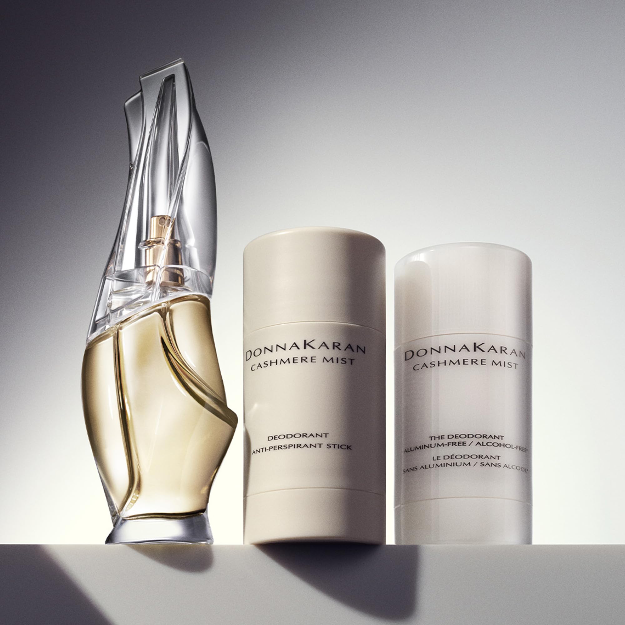 Donna Karan Cashmere Mist stick placed beside perfume demonstrating layering benefit