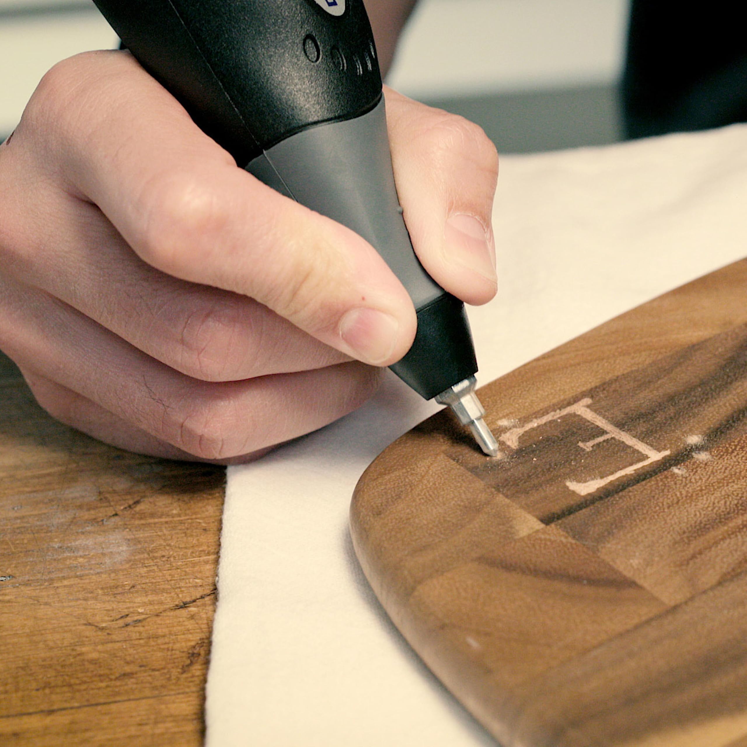 Dremel in hand next to ruler for scale demonstrating compact size