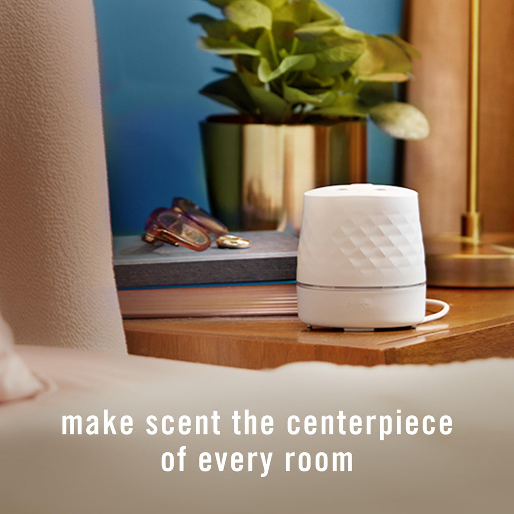 Febreze PLUG next to a hand for scale demonstrating compact, portable size