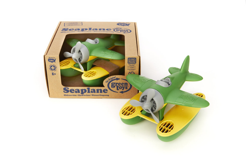 Green Toys seaplane next to a toddler hand for scale showing small-hands fit and grip development