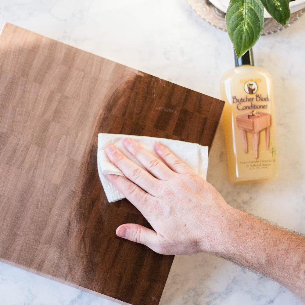 HOWARD pouring oil onto a wooden cutting board for restoration