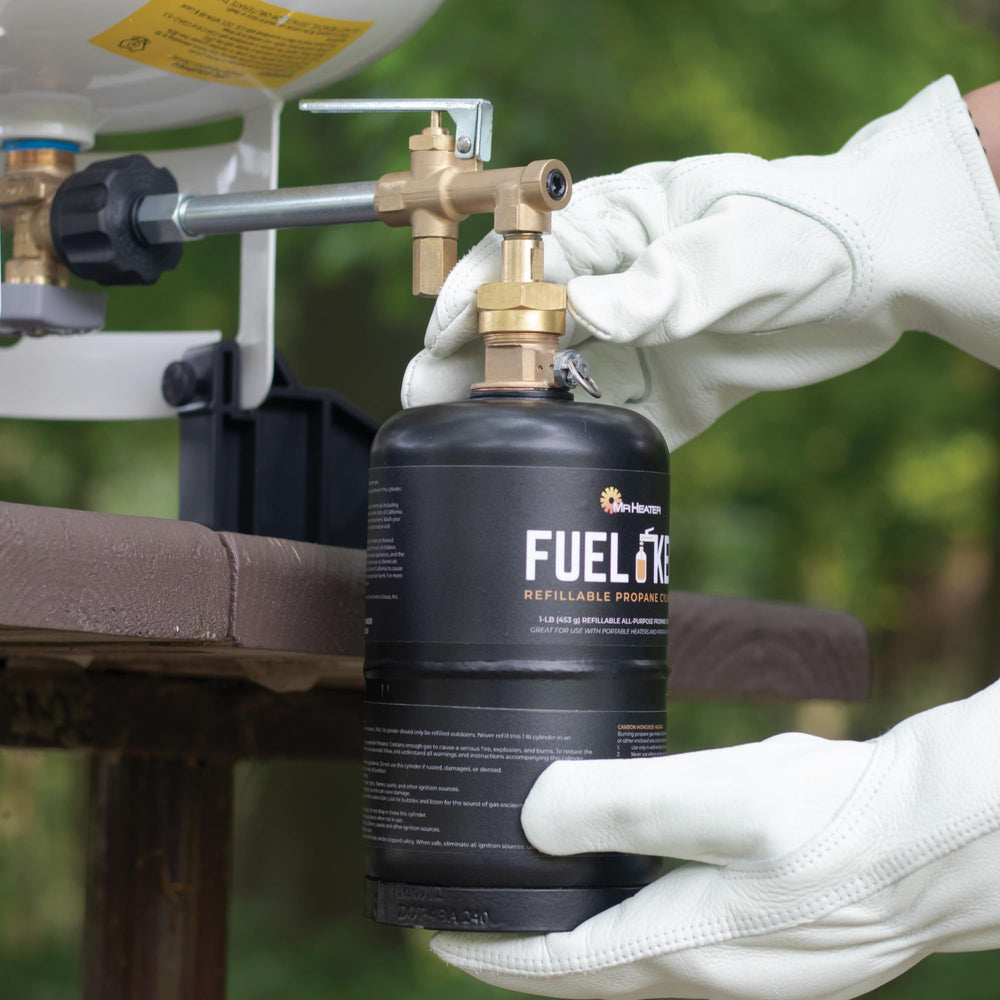 Gloved hands using Mr. Heater cylinder refill equipment outdoors.