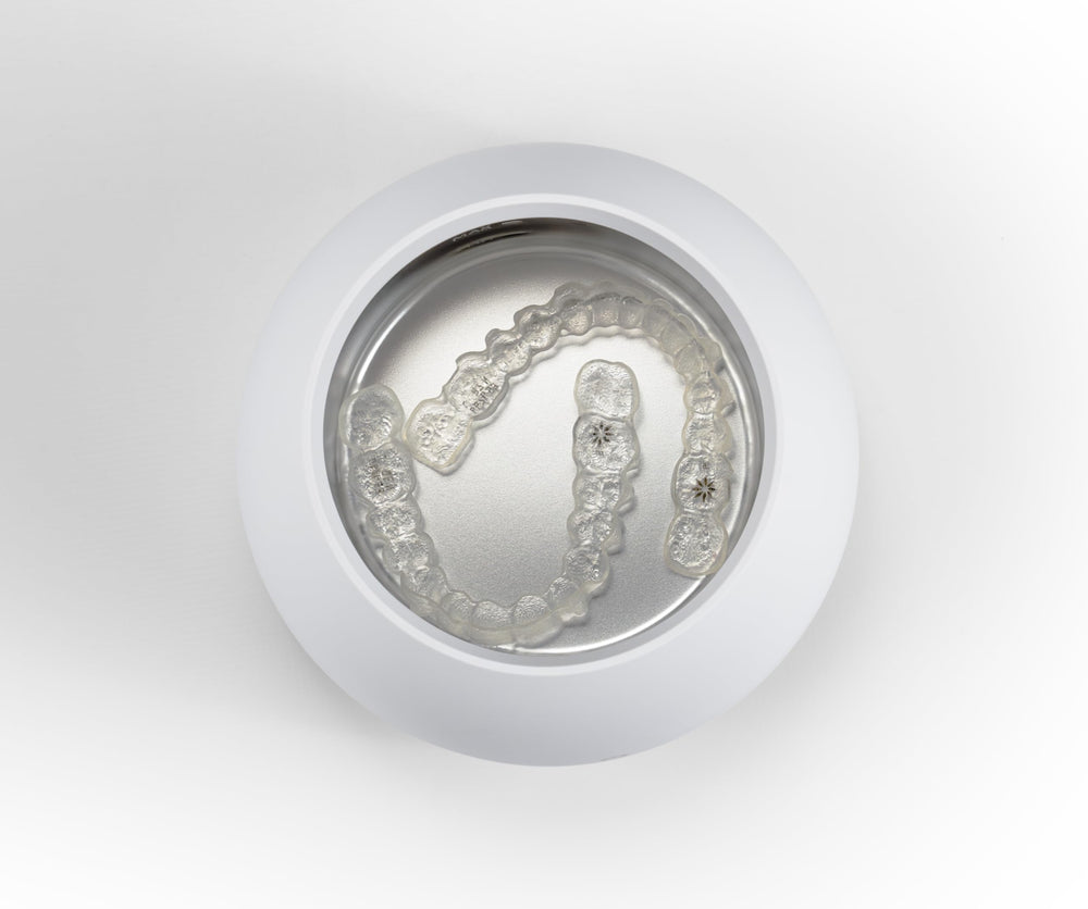 INVISALIGN cleaner next to common items showing scale and travel-friendly portability