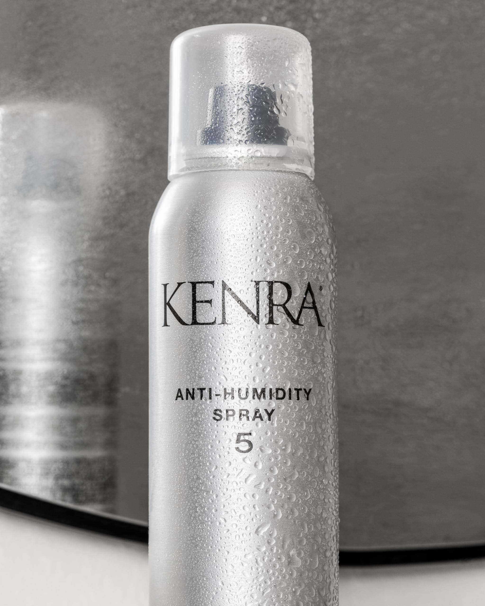 Kenra bottle beside hand showing 5oz scale and travel-friendly benefit