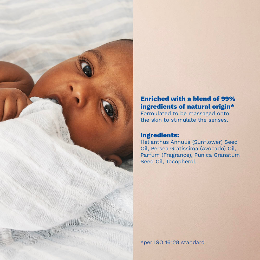 Mustela baby oil held in adult hand to show 3.38 fl. oz. scale and portability