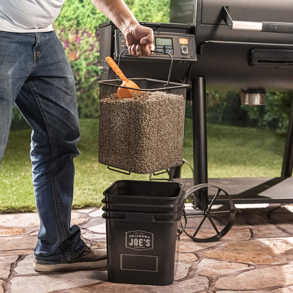 Oklahoma Joe's pellet bucket in use with scoop transferring pellets efficiently