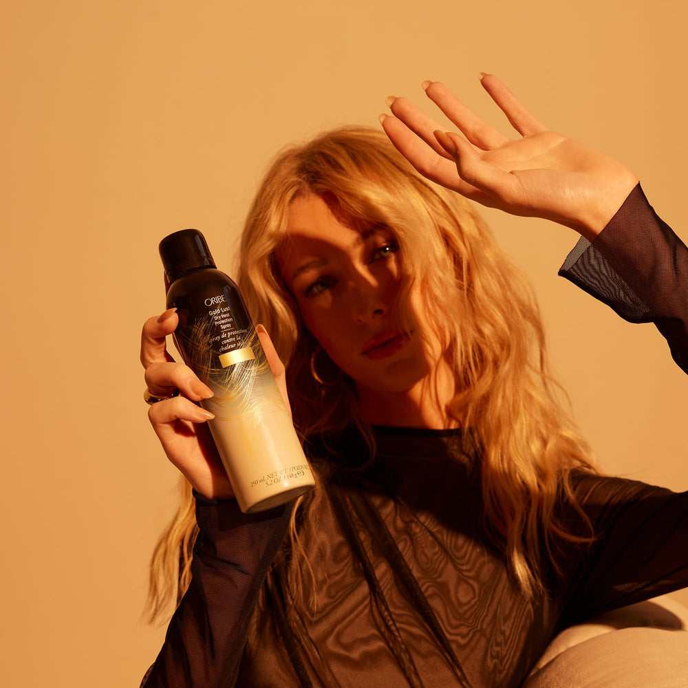 Lifestyle setting with Oribe Gold Lust by the beach evoking scent and luxury benefit