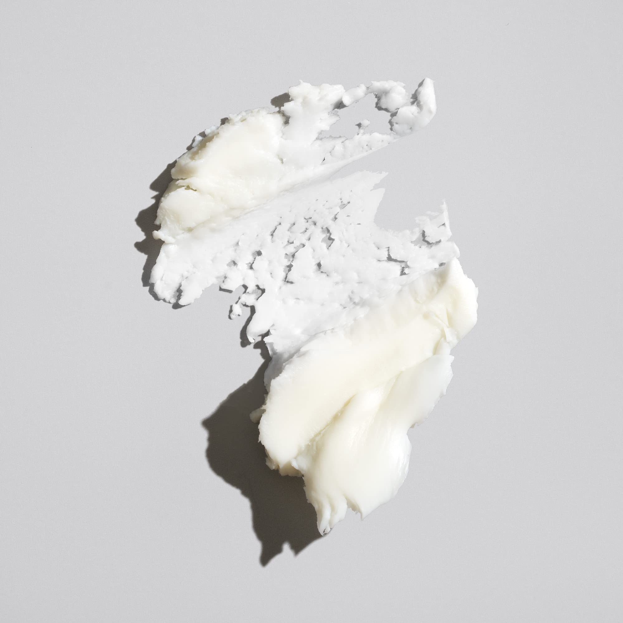 ORIBE paste texture close-up on fingers demonstrating creamy moldable grip benefit