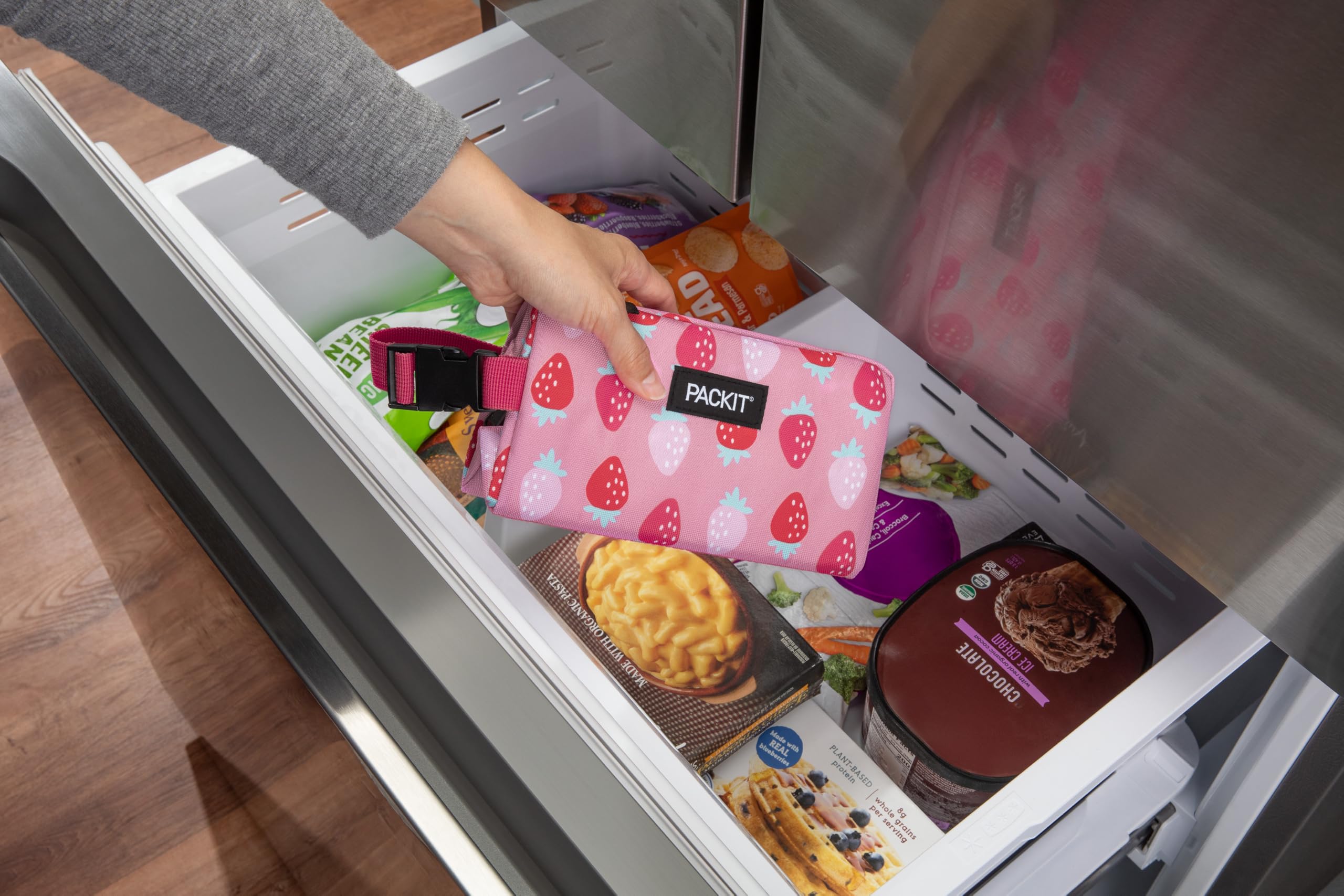 PackIt Snack Box clipped to backpack with buckle handle for hands-free carrying benefit