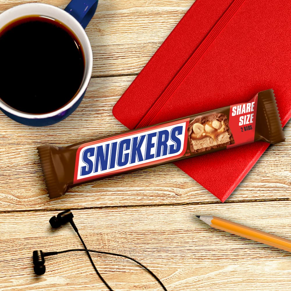 Snickers held in hand for size comparison and portion-friendly benefit
