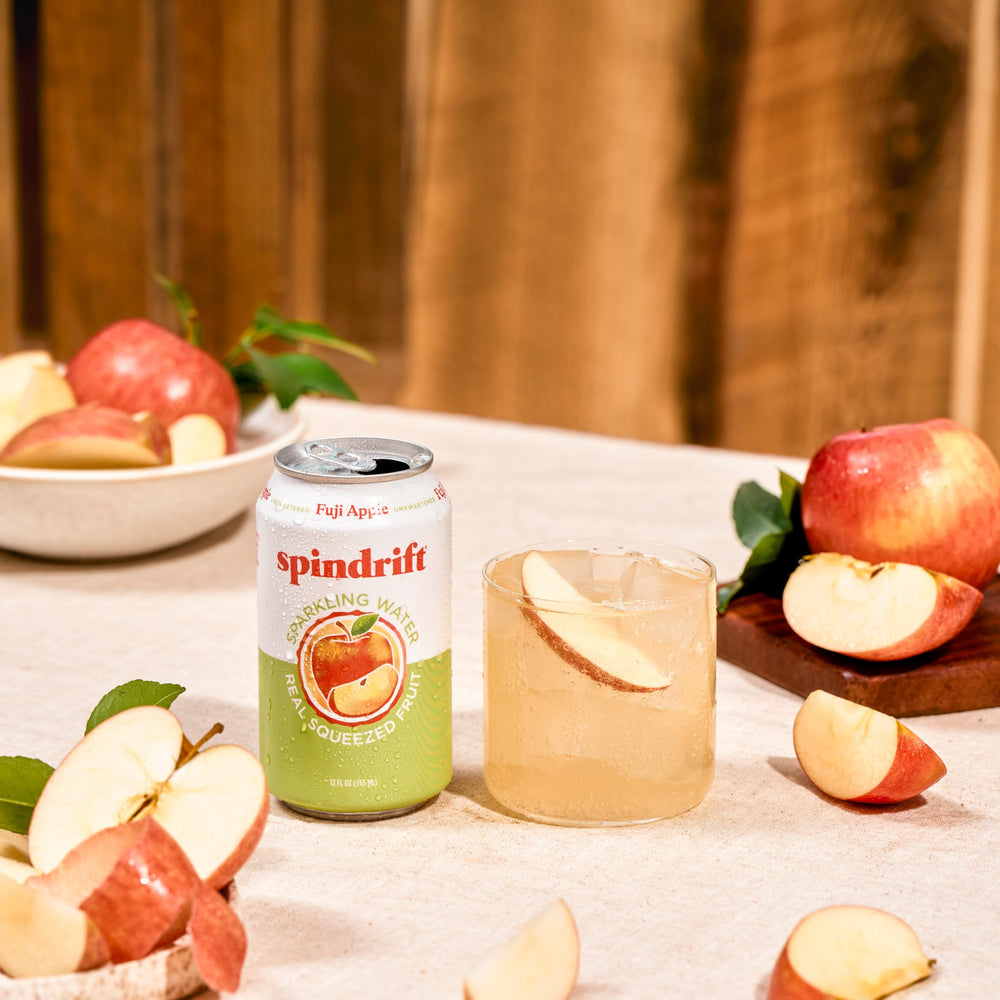 Spindrift Fuji Apple on picnic blanket with snacks suggesting social portability