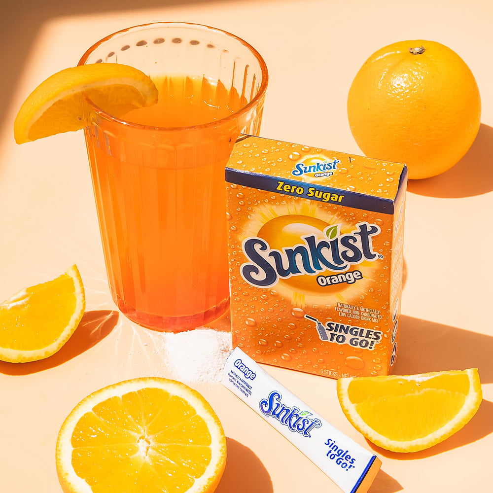 SINGLES TO GO! packet used at a picnic demonstrating portable orange flavor on-the-go