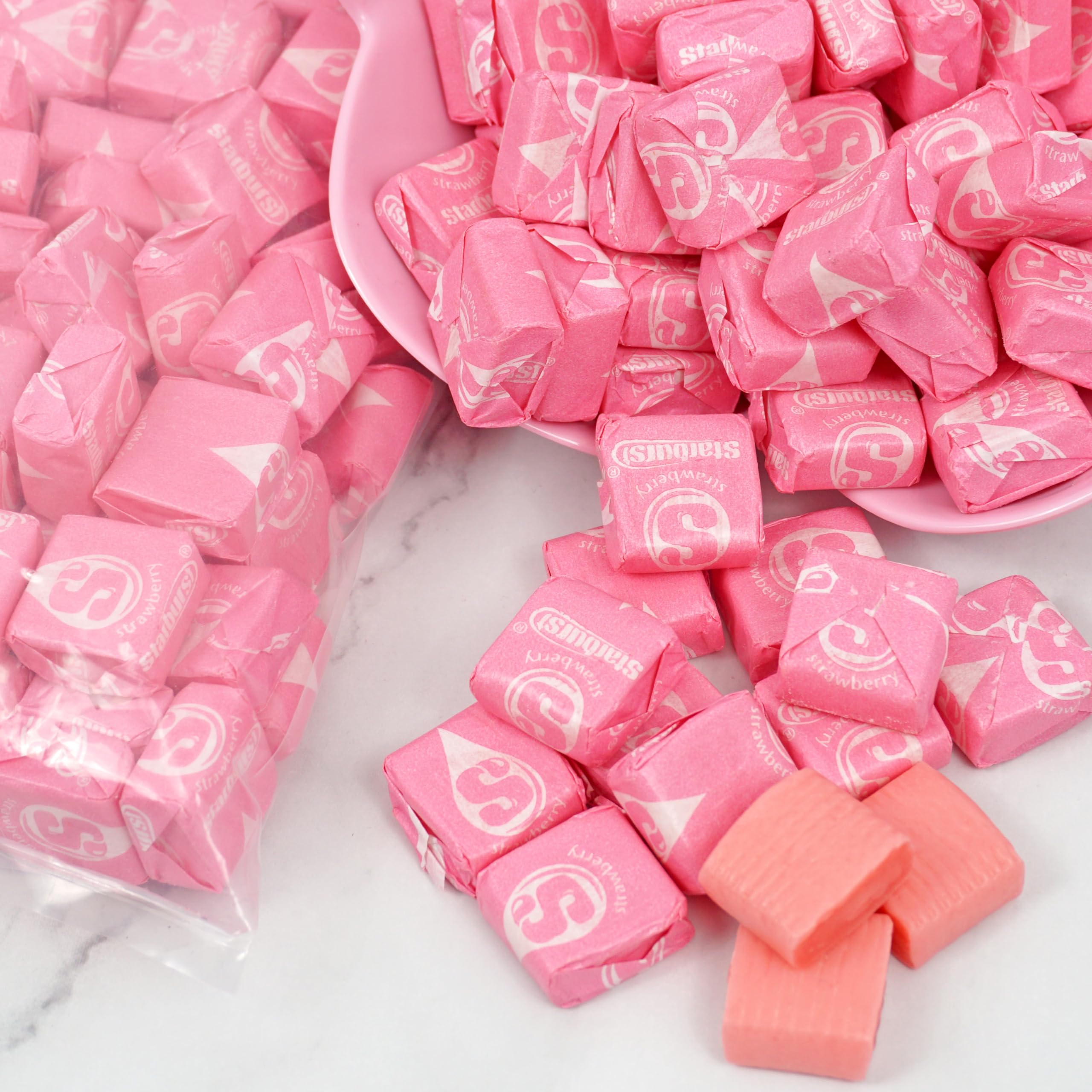 Hand holding a Starburst All Pink chew to show scale and convenience from THE HAMPTON CANDY COMPANY
