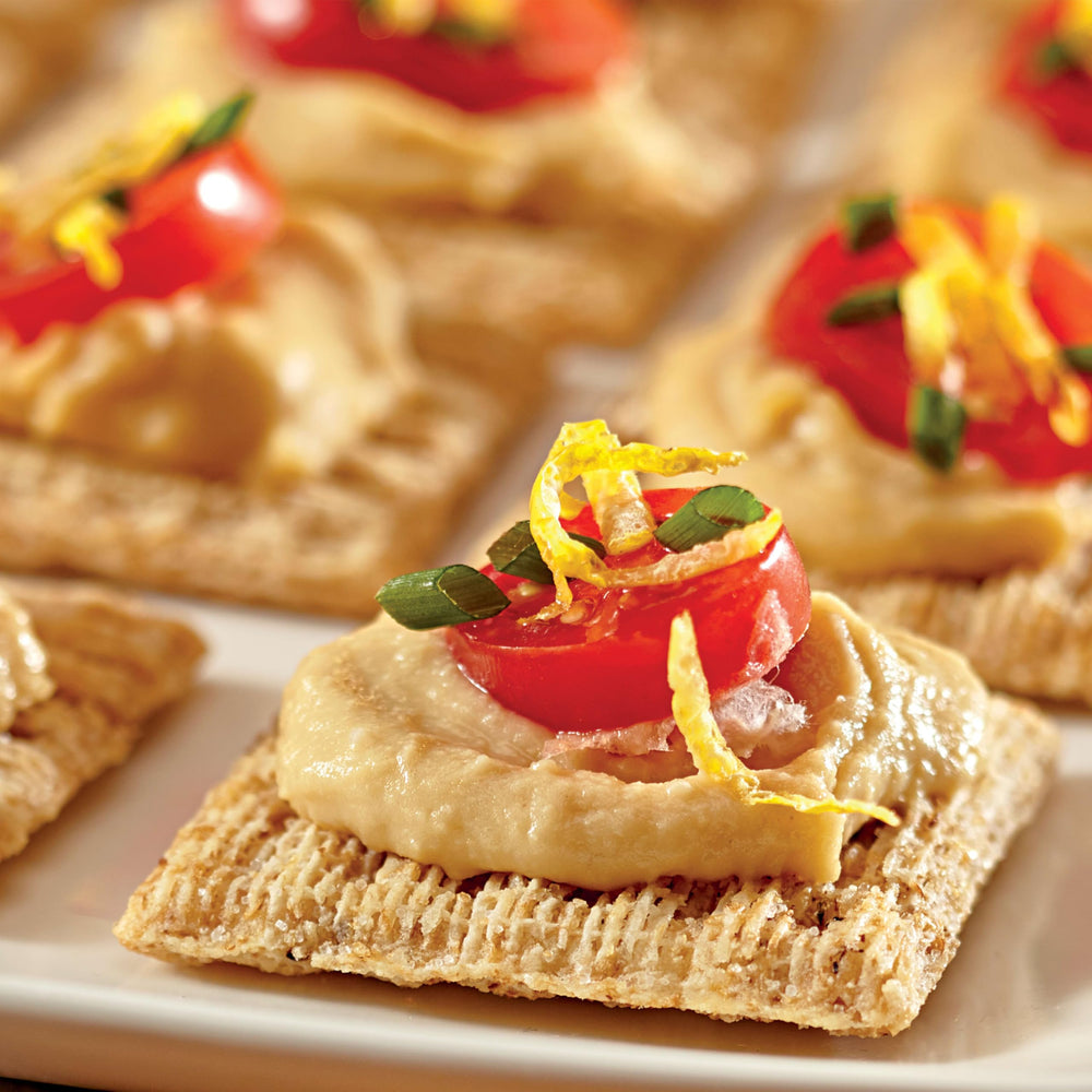 Triscuit cracker dipped in hummus demonstrating scoop and hold benefit