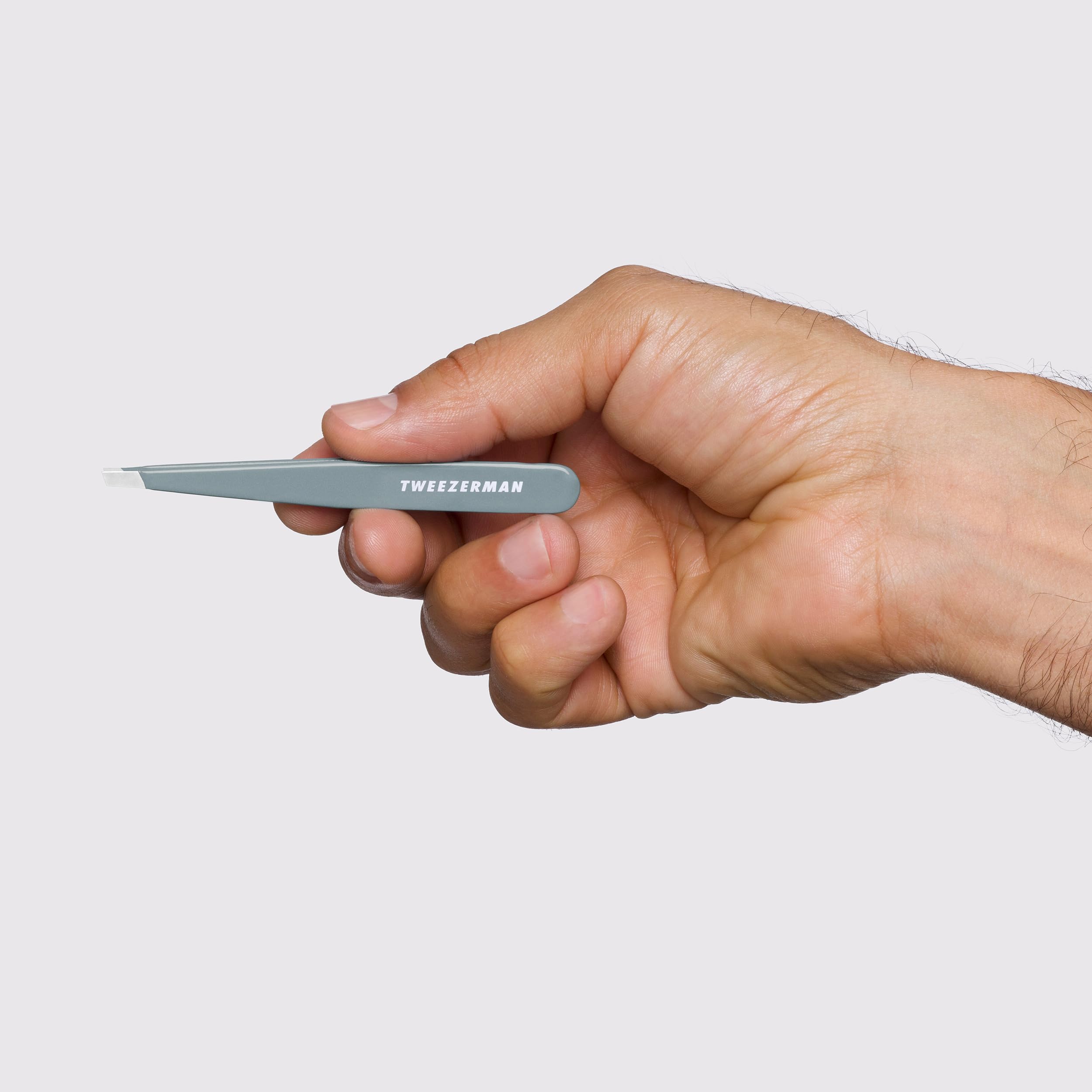 Tweezerman next to ruler showing compact size for travel convenience